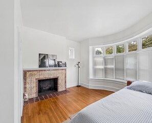 A bedroom with a fireplace, a bed, and a bay window. - Bryn Mawr 1st Floor Apartment / Near Villanova (Bryn Mawr)