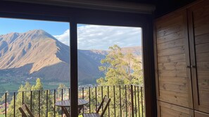 En balkon med udsigt til et bjerg, et bord og en stol.