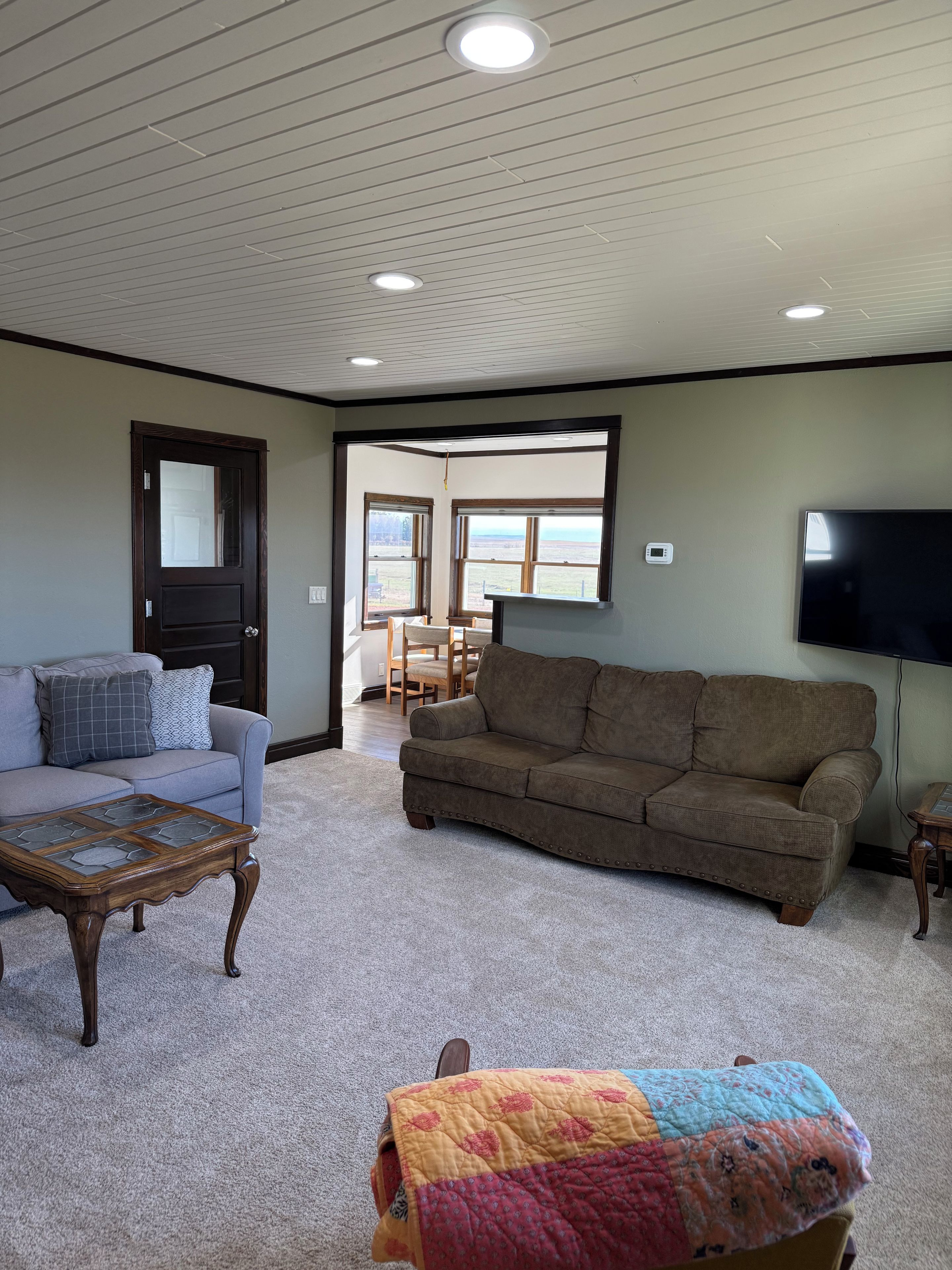 A living room with a sectional sofa, a coffee table, and a TV mounted on the wall.