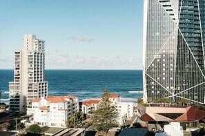 A coastal cityscape with modern high-rise buildings, a beachfront, and a parking area. - Salt and Soleil a beachside apartment in the heart of the Gold Coast (Surfers Paradise)