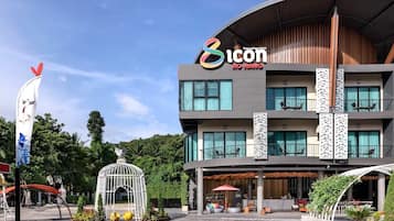 A multi-story hotel with a modern design, featuring balconies, large windows, and a central atrium with seating areas.