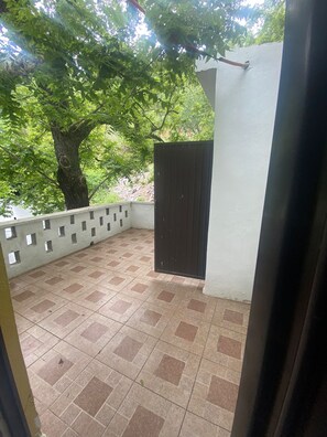 A covered outdoor area with a tiled floor, a tree, and a black gate. - New Listing (Santiago)