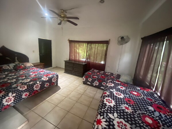 A bedroom with two beds, a dresser, a ceiling fan, and a window with curtains.