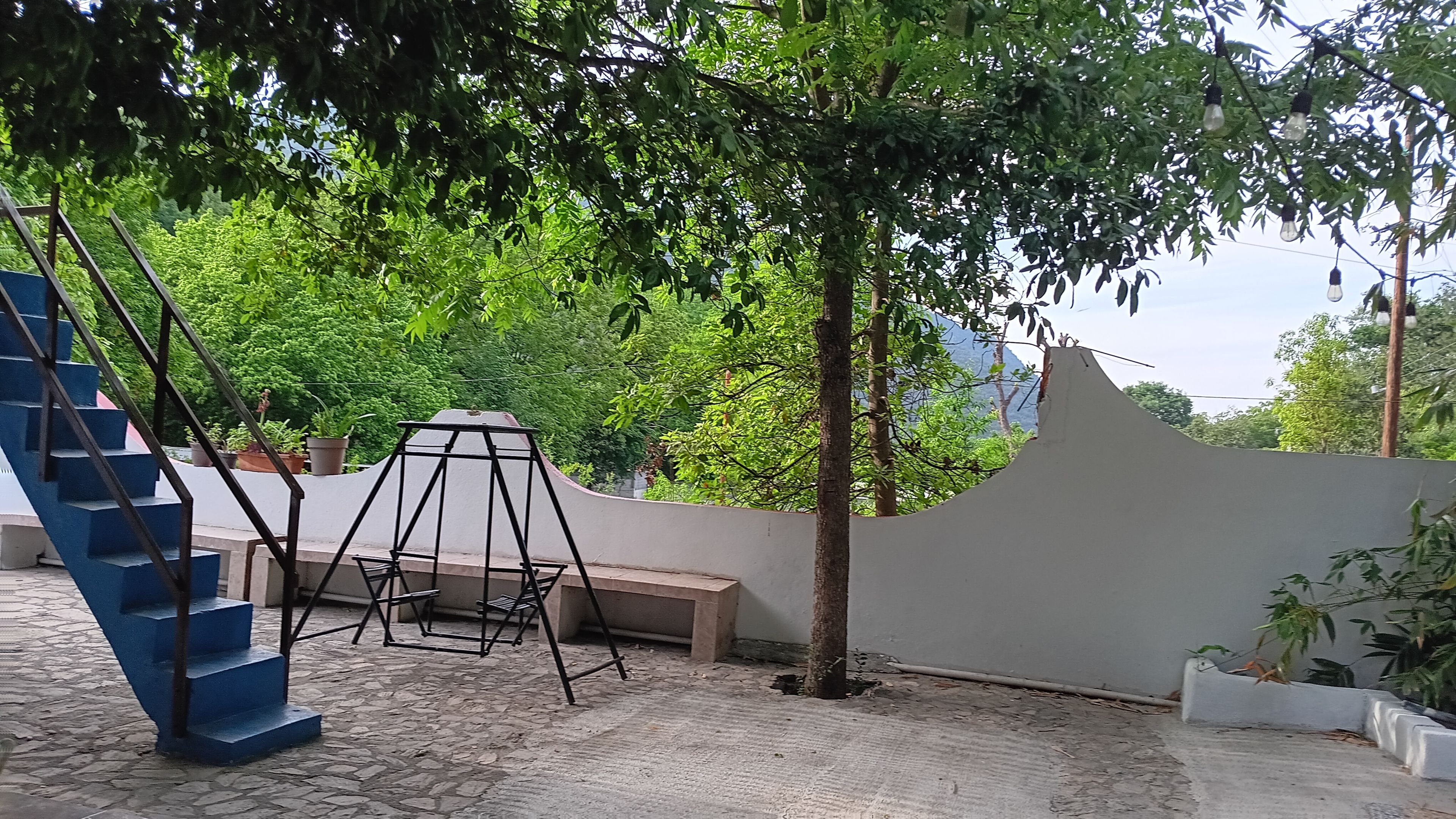 A courtyard with a swing set, a bench, and a staircase.