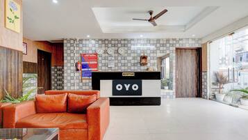 A reception area with a reception desk labeled 'OYO,' a ceiling fan, and a wall with patterned tiles.