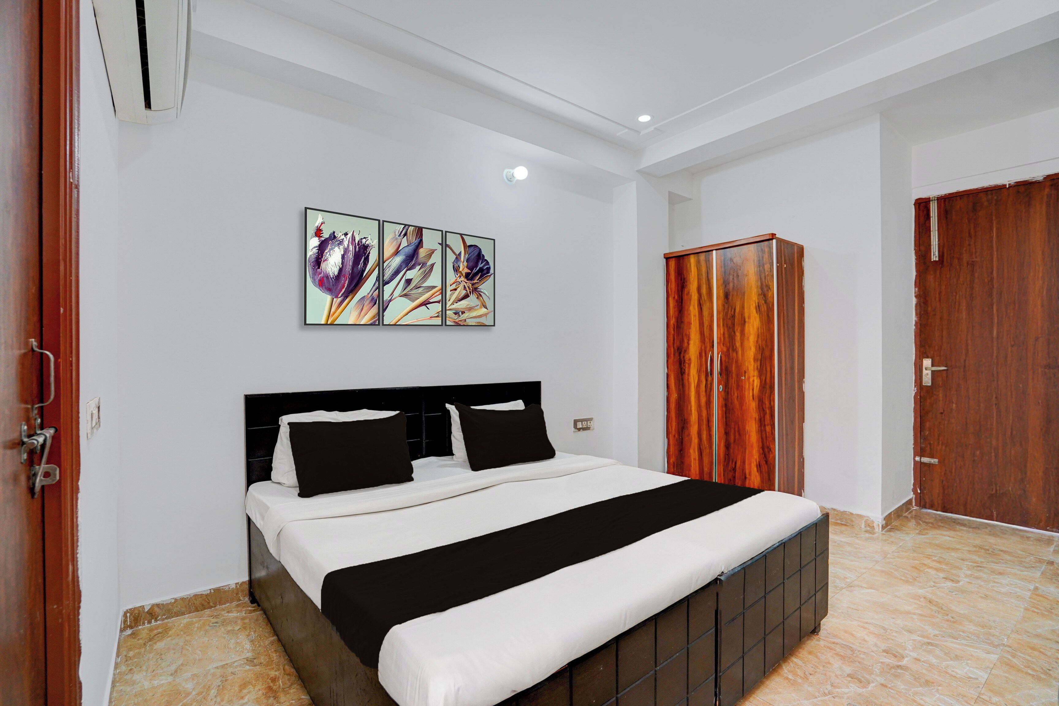 A hotel room with a bed, a wardrobe, and a wall-mounted artwork.