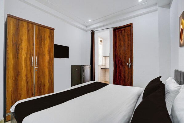A hotel room with a bed, wardrobe, and a television. - Hotel O Premier Stays (Gurugram)