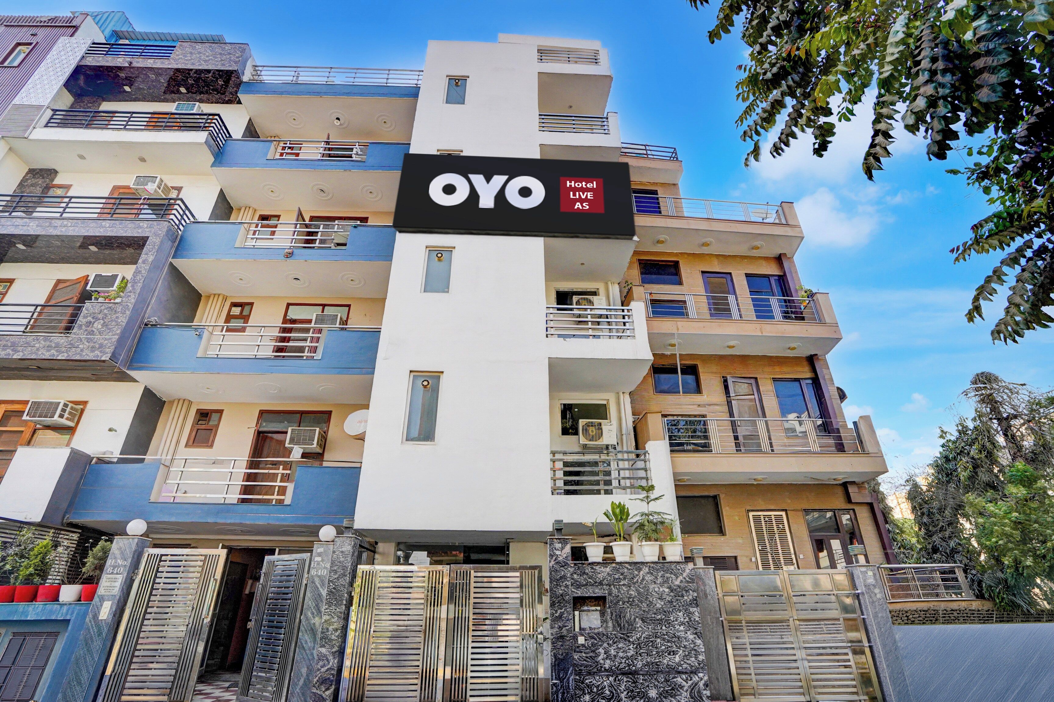 A multi-story hotel with balconies, air conditioning units, and a sign indicating 'OYO Hotel LIVE AS'.