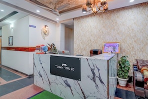 Una recepción con encimera de mármol y un cartel que dice 'OYO TOWNHOUSE'.