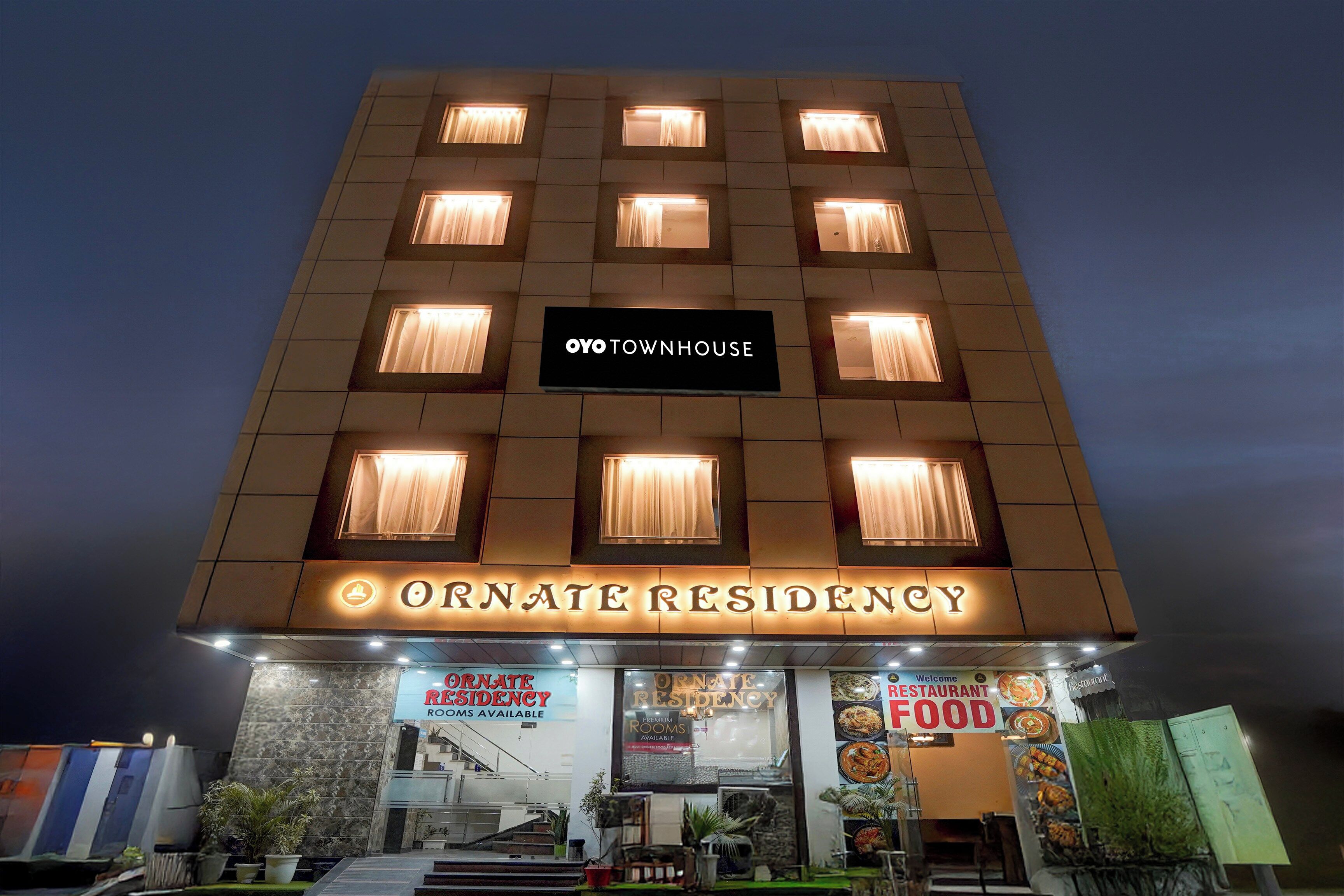 Un hotel con un letrero que dice 'OYO TOWNHOUSE' y 'ORNATE RESIDENCY', indicando una opción de alojamiento de categoría superior.