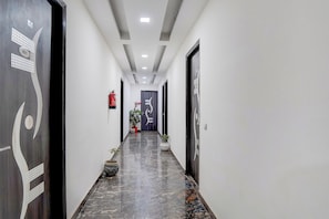 Un pasillo con piso de mármol, puertas con paneles decorativos y plantas en macetas.