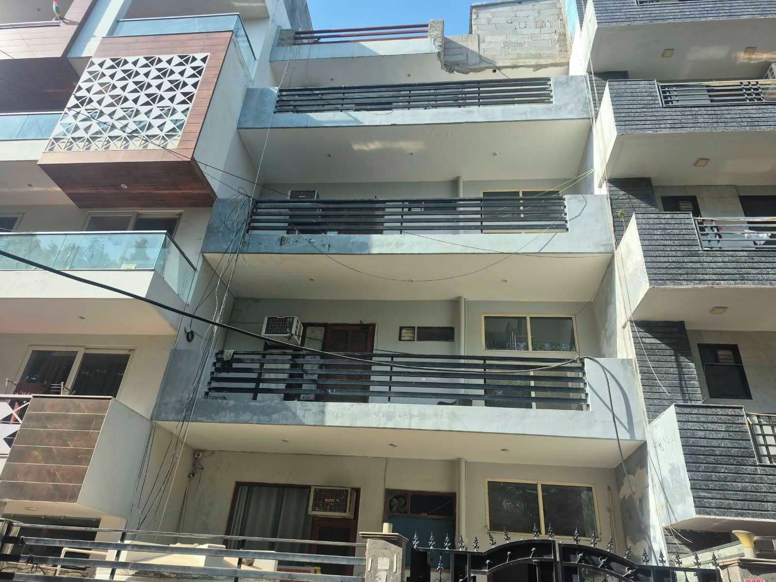 Un immeuble résidentiel à plusieurs étages, doté de balcons, de fenêtres et d’une entrée sécurisée par un portail.