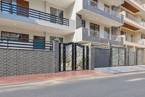 Un edificio residencial de varios pisos con entrada protegida por un portón, balcones y fachada de piedra.