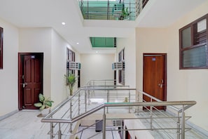 A spacious corridor with a glass railing, doors numbered 08 and 11, and air conditioning units on the walls. - Hotel O Shivik Stays (Gurugram)