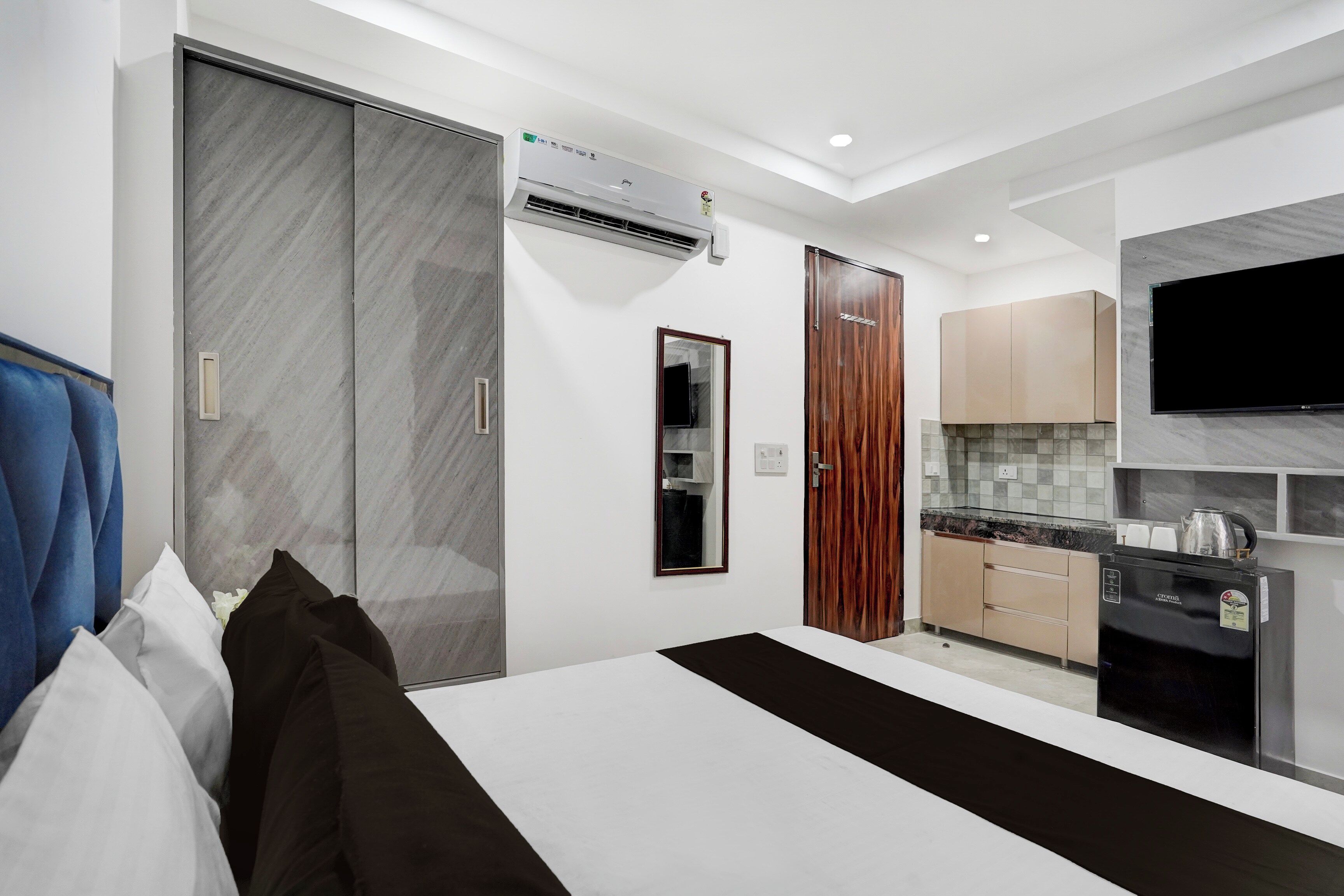 Un dormitorio moderno con cama, armario y una pequeña cocina.