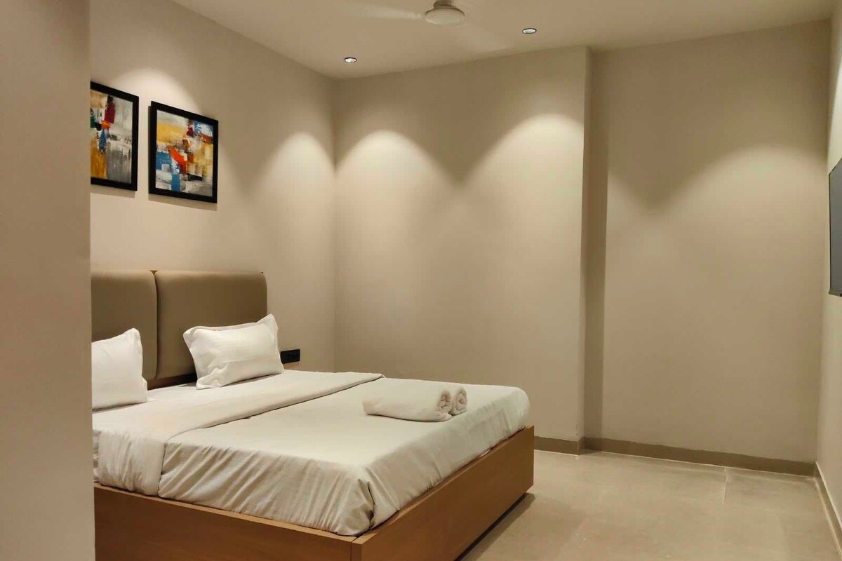 A modern bedroom with a bed, pillows, and artwork on the wall.