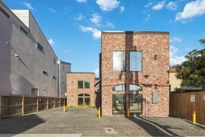 A multi-story building with a brick facade, a gated entrance, and a clear sky. - SoHo Vibes - EaDo Lofts #B (Houston)