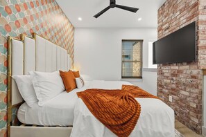 Ein Hotelzimmer mit einem Bett, einem an der Wand befestigten Fernseher und einer Ziegelwand.