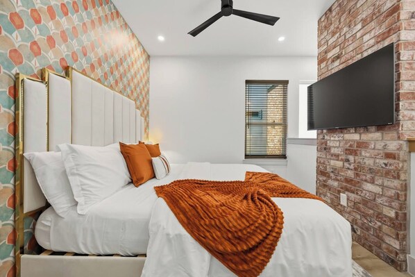 A hotel room with a bed, a television mounted on the wall, and a brick accent wall. - SoHo Vibes - EaDo Lofts #2 (Houston)