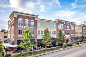 A multi-story building with a brick facade, storefronts on the ground floor, and a clear sky. - SoHo Vibes - EaDo Lofts #2 (Houston)