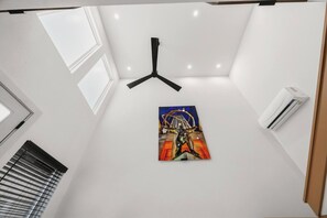 A room with a ceiling fan, a window with blinds, and a wall-mounted air conditioner. - SoHo Vibes - EaDo Lofts #2 (Houston)