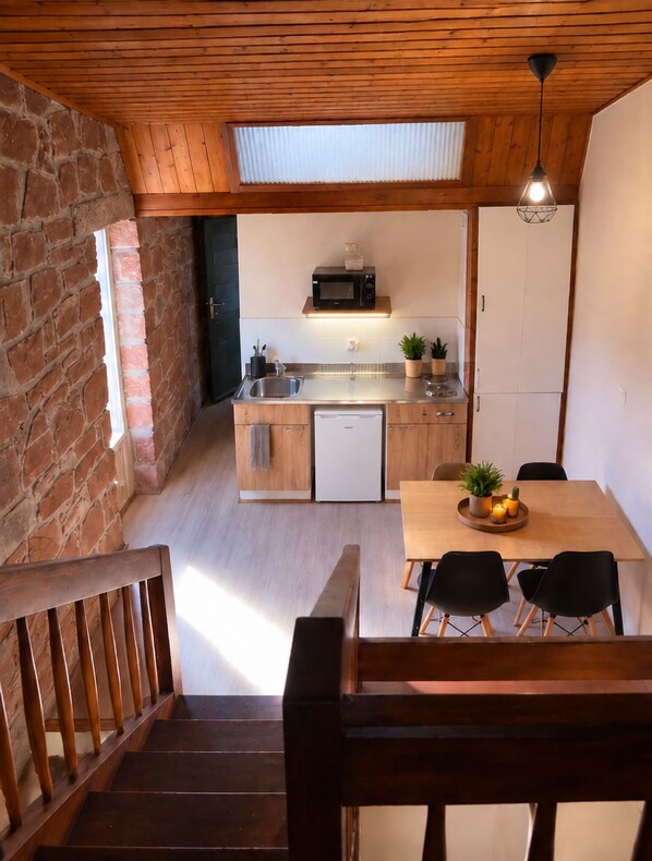 A kitchen with a wooden ceiling, a microwave, a sink, and a dining area with a table and chairs. - New Listing (Albé)