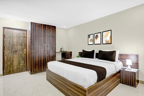 A hotel room with a large bed, a wardrobe, a bedside table with a lamp, and three framed artworks on the wall. - Hotel O by OYO Cdr Grand (Guntur)