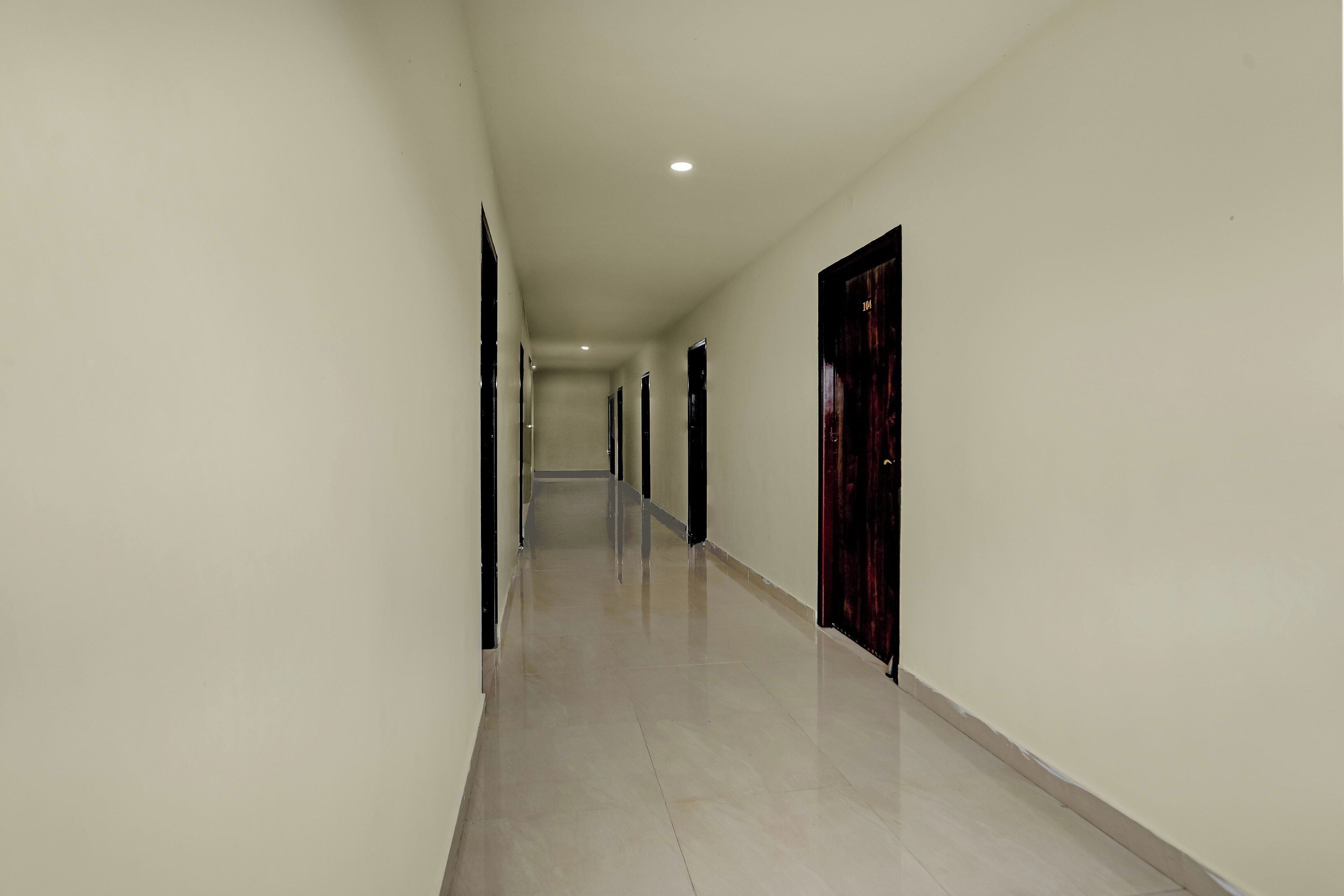 A long, narrow hallway with a tiled floor and white walls.