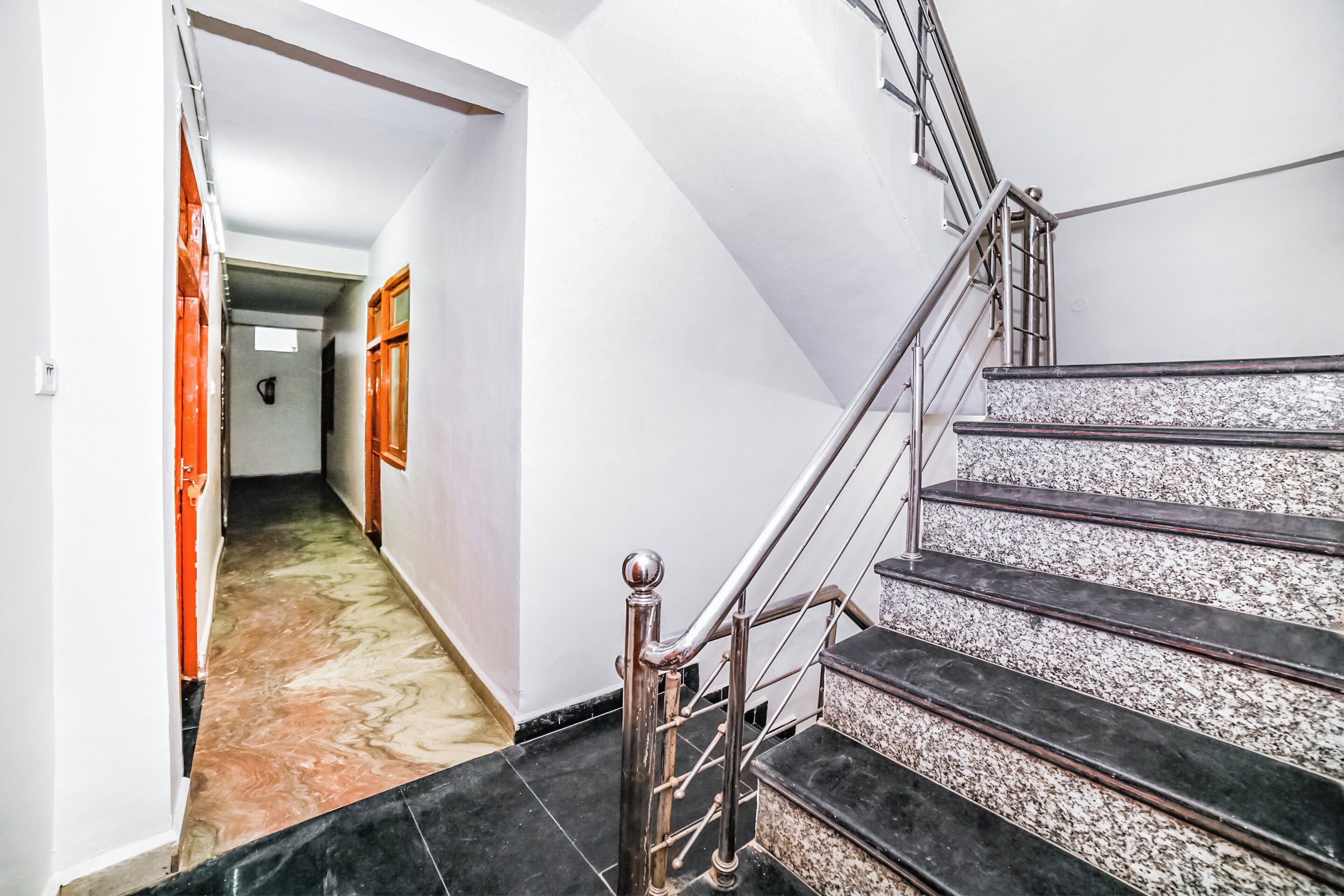 A staircase with metal railings and a marble floor leading to a room.