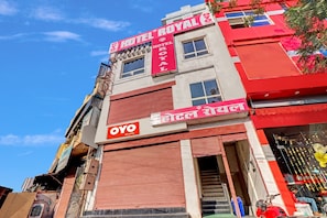 A hotel with a red facade, multiple windows, and a visible entrance. - Hotel O Royal (Gwalior)