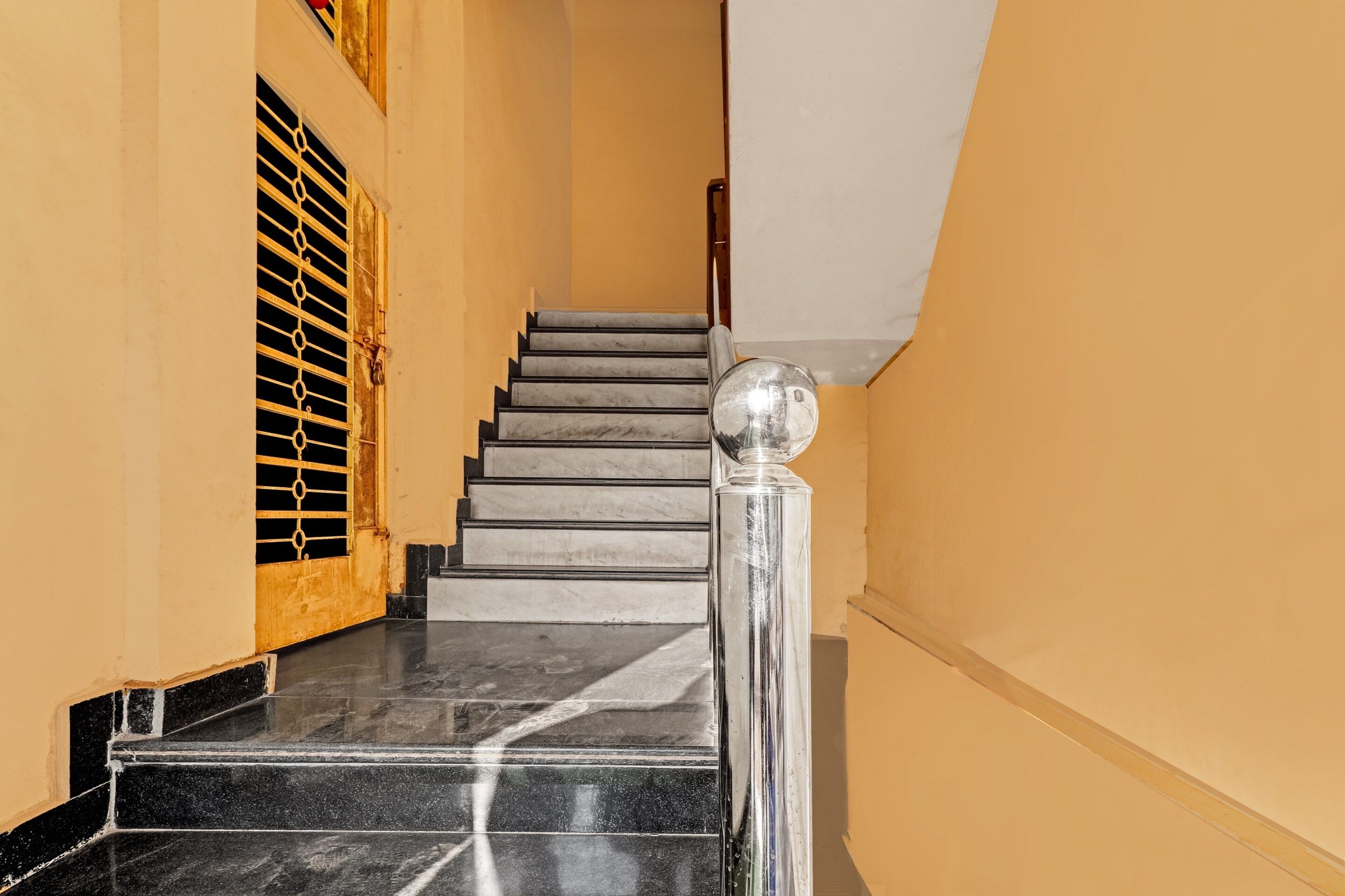 Una escalera con escalones de mármol y barandilla de metal, que conduce a un piso superior.