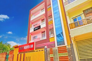 Ein mehrstöckiges Hotel mit einem auffälligen roten Schild für 'Hotel Heaven Inn' und einem kleineren Schild für 'OYO Hotel Heaven Inn' über dem Eingang.