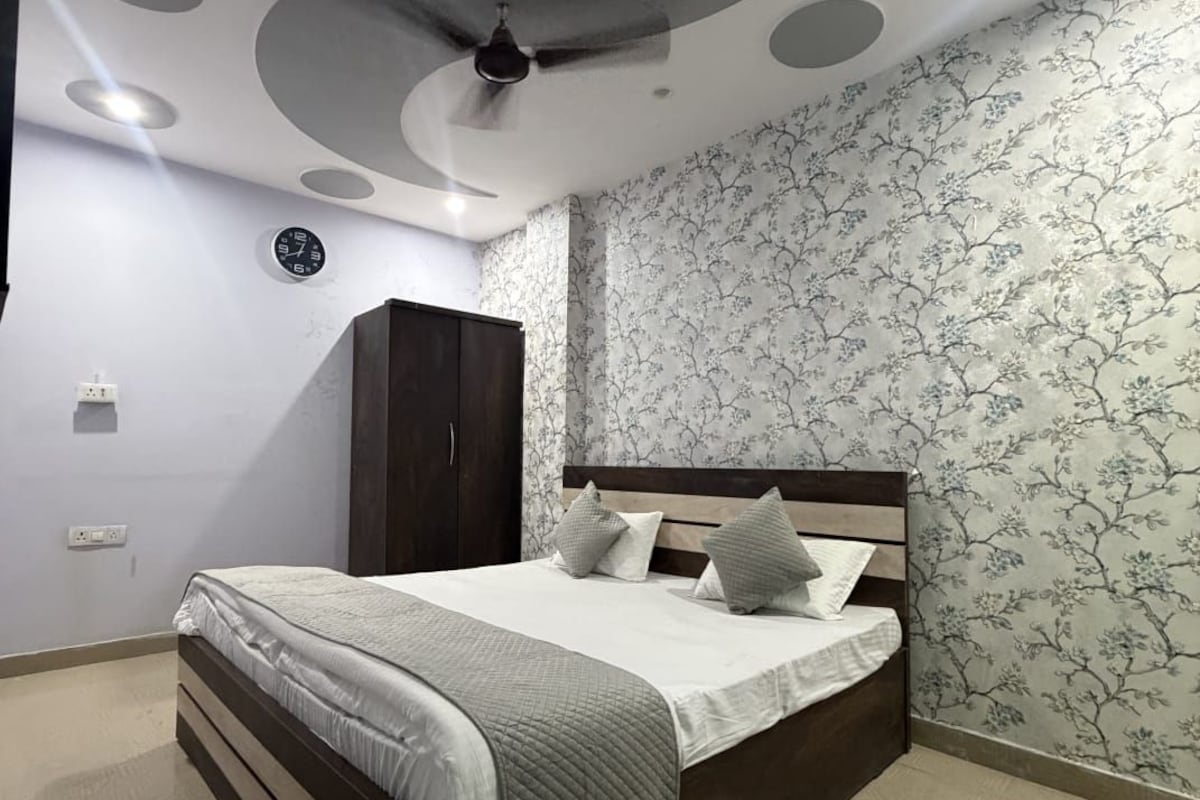 A bedroom with a bed, a wardrobe, a ceiling fan, and a wall clock.