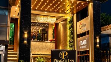 Exterior del Pragati Inn con señalización iluminada para habitaciones, salón y salas de banquetes.