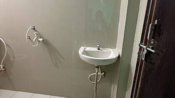 A bathroom with a white sink, a handheld showerhead, and a door with a handle.