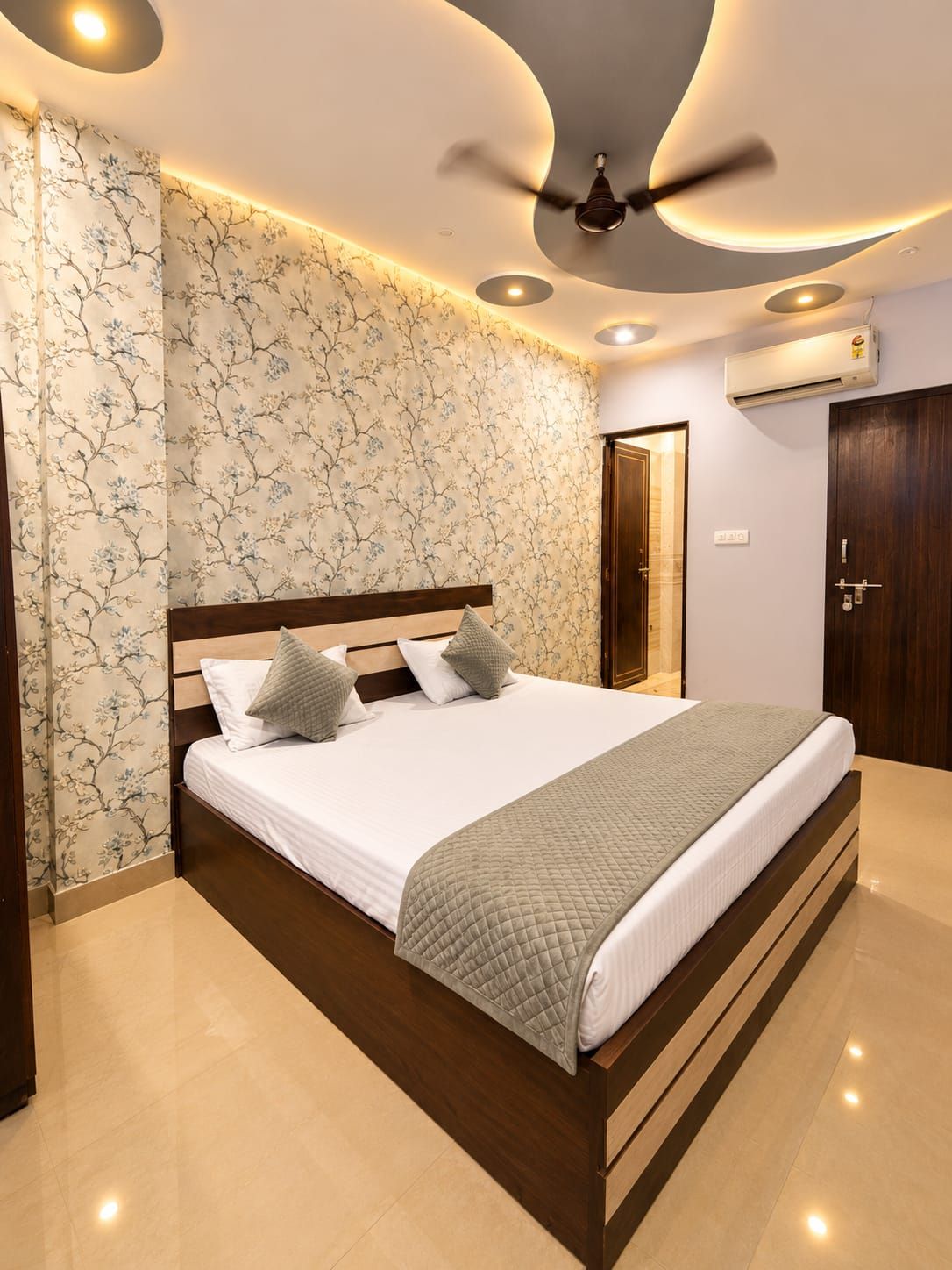 Un dormitorio moderno con una cama grande, ventilador de techo y aire acondicionado de pared.