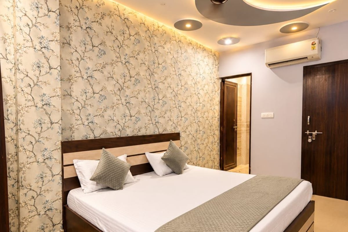 Un dormitorio moderno con una cama grande, ventilador de techo y aire acondicionado de pared.