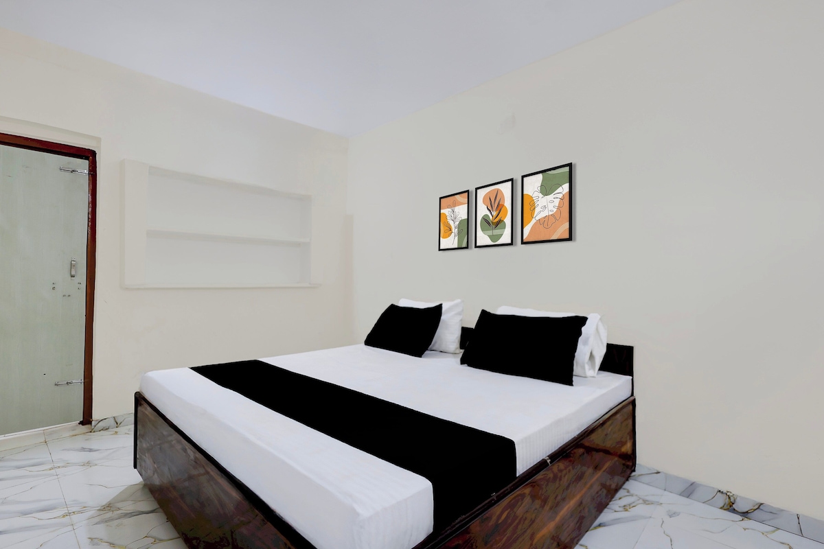 A bedroom with a bed, a door, and three framed artworks on the wall.