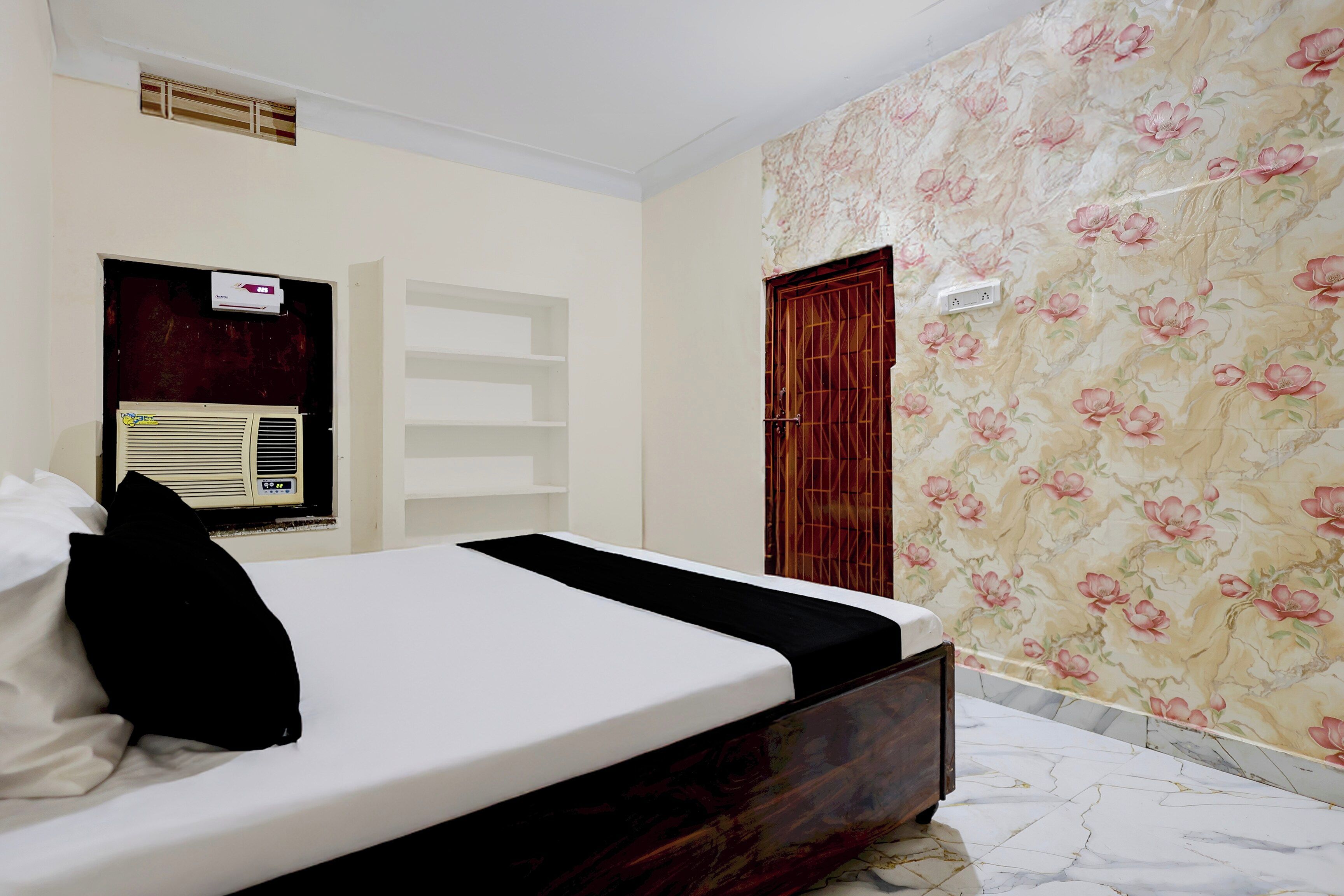 A bedroom with a bed, an air conditioning unit, a wardrobe, and a door.