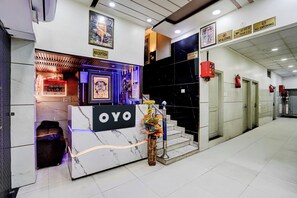 A hotel reception area with a marble counter, a reception desk, and a staircase leading to the upper floors. - Hotel O ANANT ONE HOTEL AND BANQUETS (Ghaziabad)