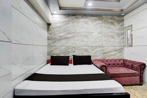 A bedroom with a bed, a red sofa, and a marble-patterned wall. - Hotel O ANANT ONE HOTEL AND BANQUETS (Ghaziabad)