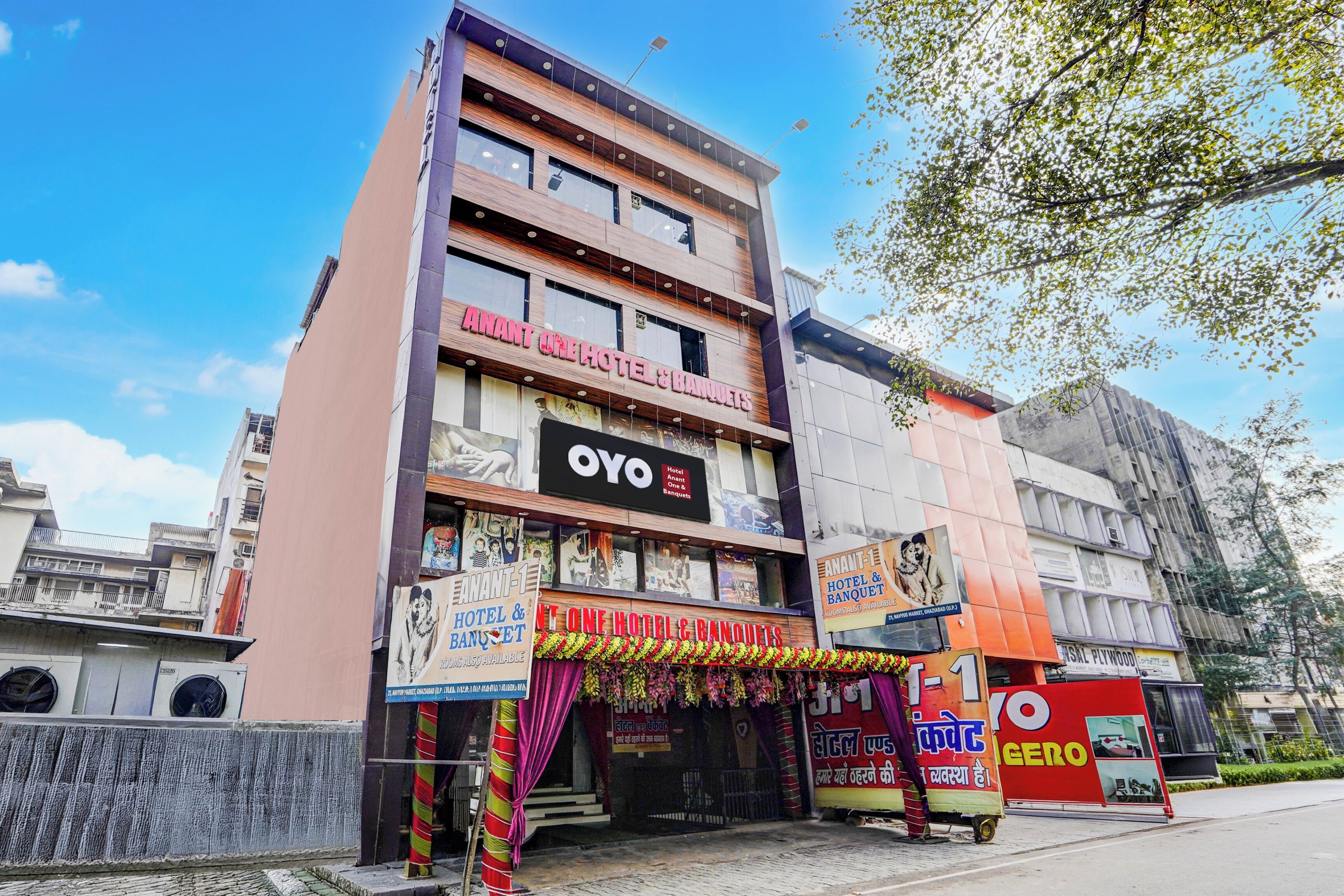A multi-story building with signage for 'Anant One Hotel & Banquets' and 'Oyo Hotel & Banquets'.
