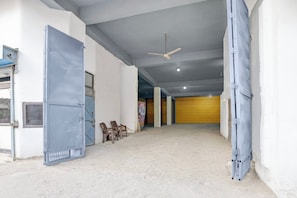 A hallway with a ceiling fan, a door, and a poster on the wall. - Hotel O Sukoon Guest House (Modinagar)
