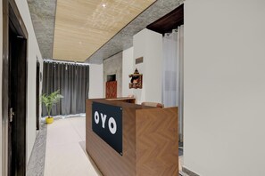 Un comptoir d’accueil avec une enseigne indiquant « OYO », situé dans le hall moderne d’un hôtel, avec un sol en marbre et un espace d’accueil.