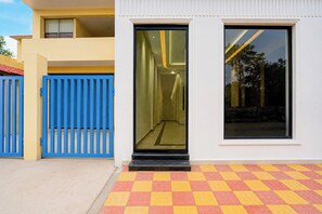 Un edificio moderno con un portón azul, puerta de cristal y piso con estampado de cuadros.