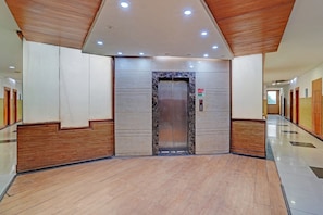 A modern elevator with a marble finish, flanked by wooden paneling and a polished floor. - Hotel O One Hotel (Ghaziabad)