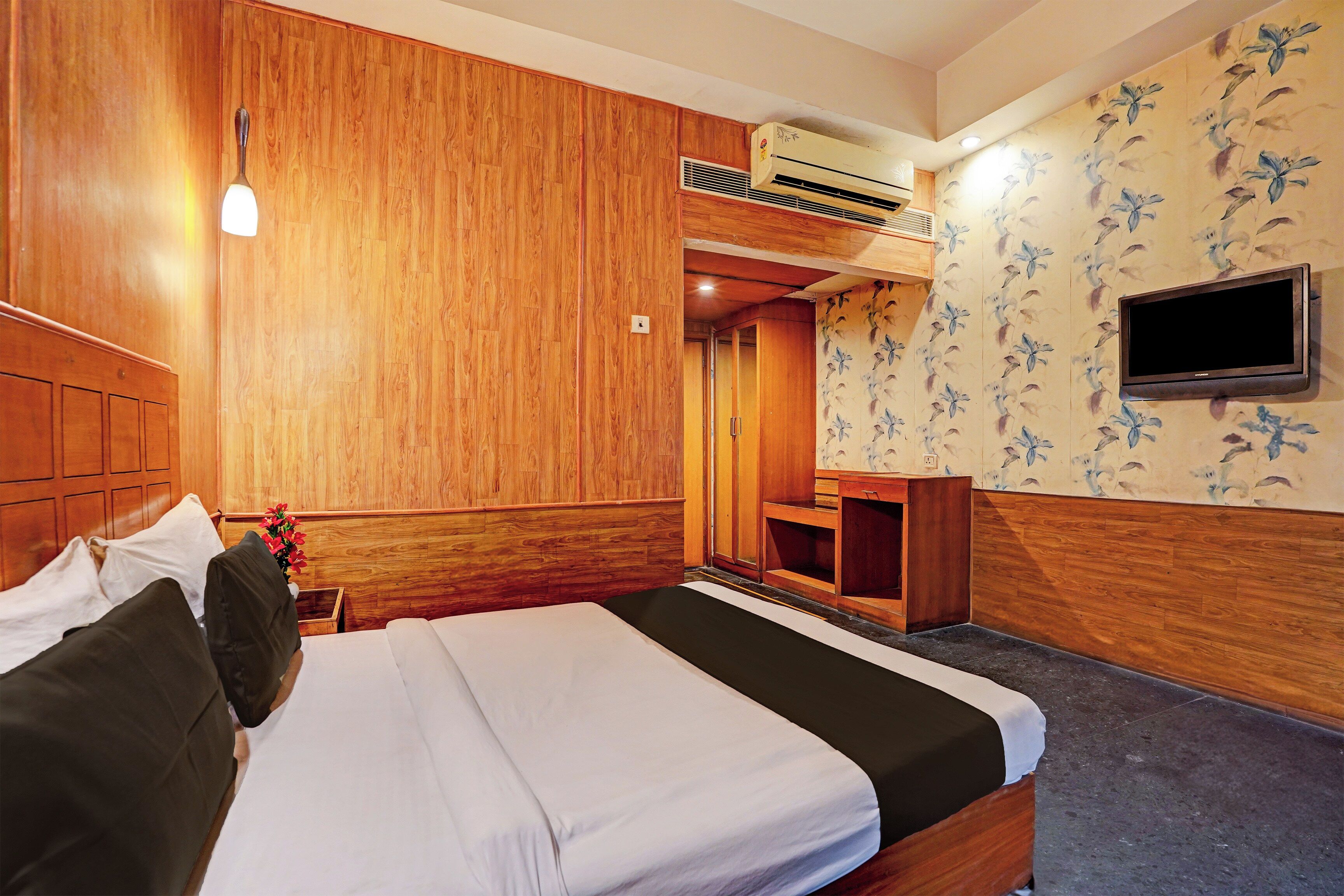 A hotel room with a bed, a desk, a television, and a shower area.