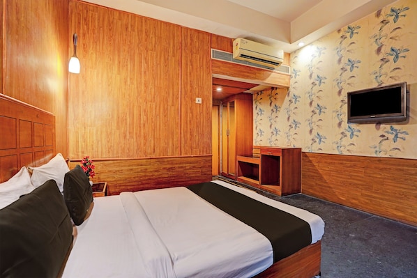 A hotel room with a bed, a desk, a television, and a shower area. - Hotel O One Hotel (Ghaziabad)