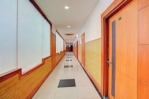 A long, narrow hallway with doors on both sides, leading to individual rooms. - Hotel O One Hotel (Ghaziabad)