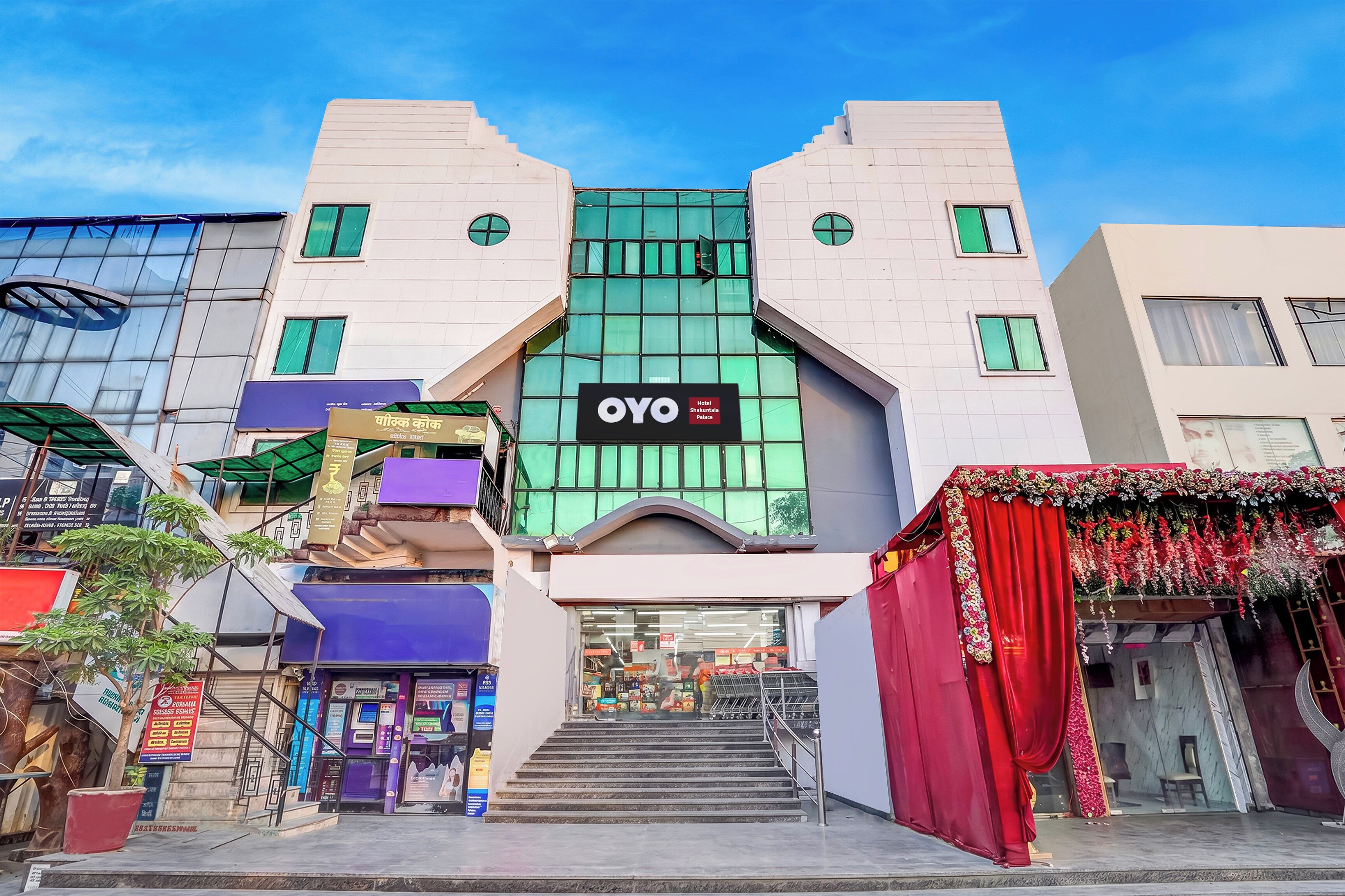 Un hotel con un llamativo letrero 'OYO', una escalera que conduce a la entrada y un escaparate con varios carteles.